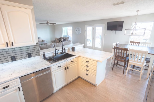 kitchen featuring sink, decorative light fixtures, stainless steel dishwasher, kitchen peninsula, and light hardwood / wood-style floors