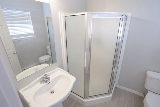 bathroom with sink, hardwood / wood-style floors, an enclosed shower, and toilet