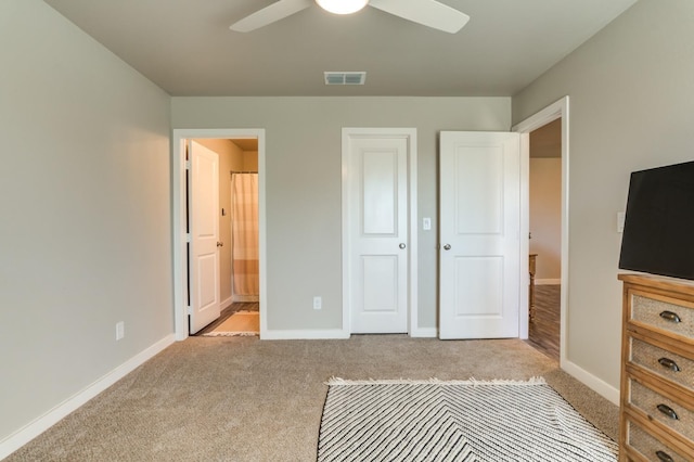 unfurnished bedroom with connected bathroom, light colored carpet, and ceiling fan