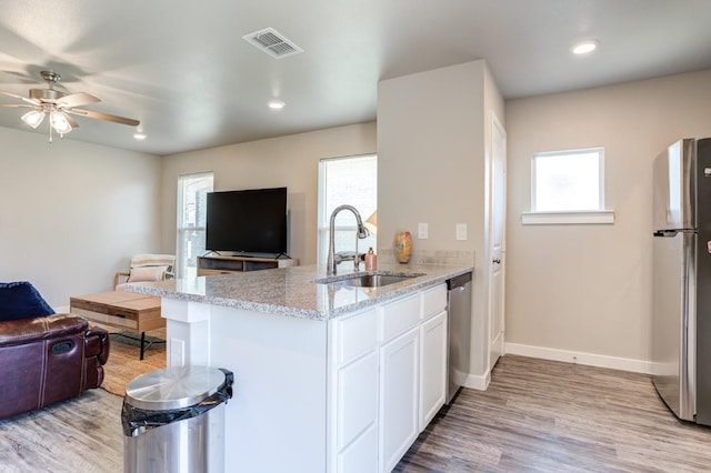 kitchen featuring sink, white cabinetry, stainless steel appliances, light stone counters, and light hardwood / wood-style floors