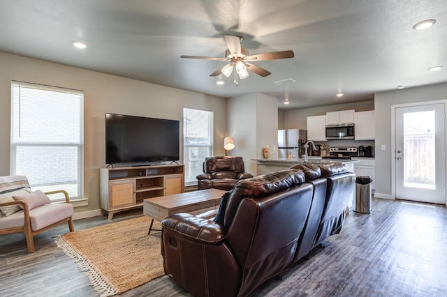 living room featuring ceiling fan, dark hardwood / wood-style floors, and sink