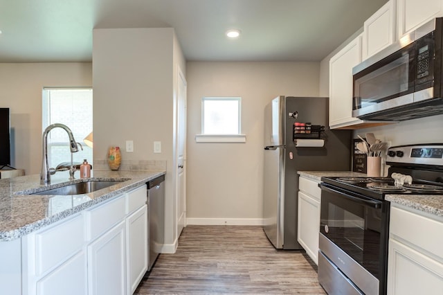 kitchen with stainless steel appliances, white cabinetry, sink, and kitchen peninsula