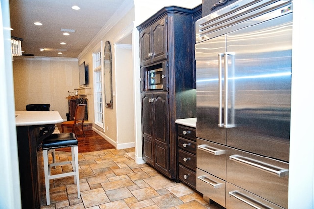 kitchen with built in appliances, crown molding, and dark brown cabinetry