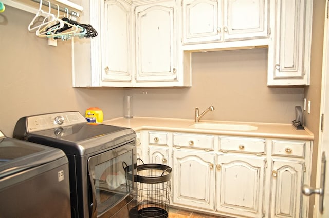 clothes washing area with cabinets, sink, and washing machine and clothes dryer