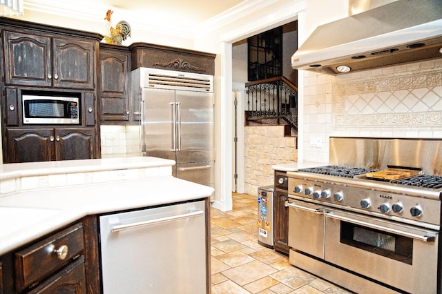 kitchen with extractor fan, tasteful backsplash, built in appliances, dark brown cabinetry, and crown molding