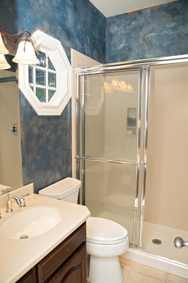 bathroom featuring toilet, vanity, tile patterned floors, and a shower with shower door