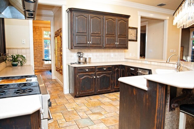 kitchen featuring dark brown cabinetry, sink, ornamental molding, and kitchen peninsula