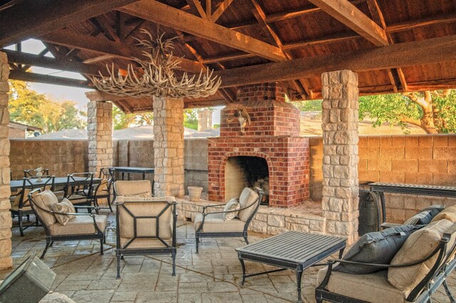 view of patio featuring an outdoor brick fireplace and a gazebo