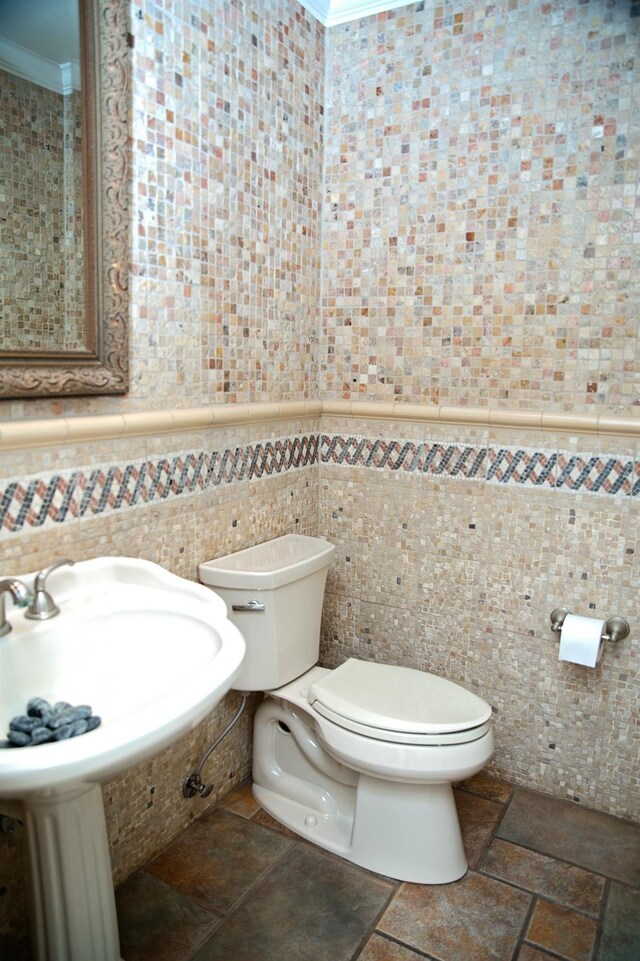 bathroom with tile walls, sink, ornamental molding, and toilet