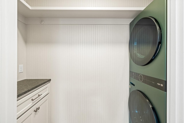 laundry area with cabinets and stacked washing maching and dryer