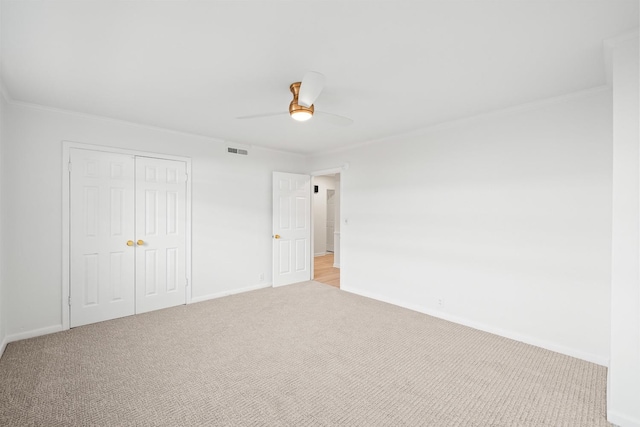 unfurnished bedroom featuring crown molding, light colored carpet, a closet, and ceiling fan