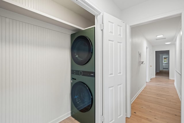 laundry room with stacked washer / drying machine and light hardwood / wood-style floors