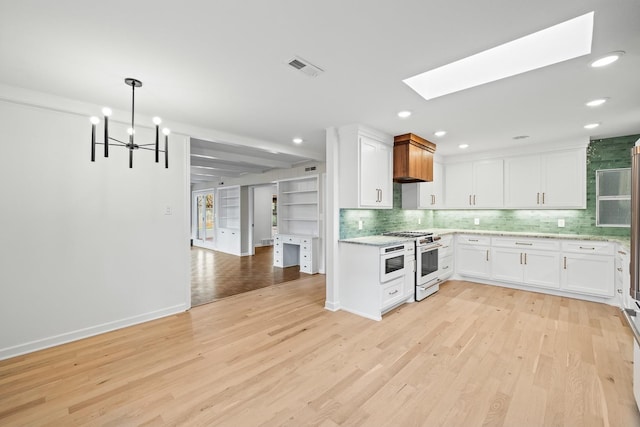 kitchen featuring pendant lighting, a skylight, white cabinets, high end range, and light hardwood / wood-style floors