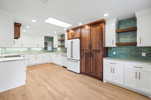 kitchen featuring white appliances, a skylight, tasteful backsplash, light hardwood / wood-style floors, and white cabinets