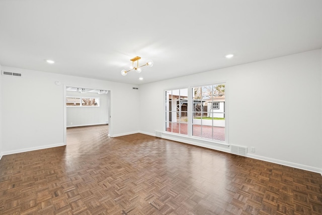 empty room featuring dark parquet floors and a notable chandelier