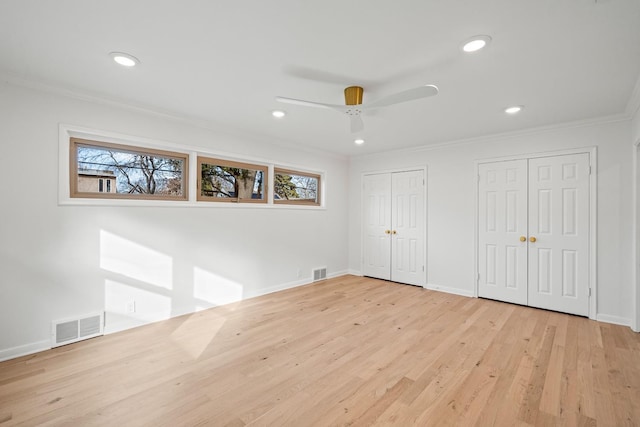 unfurnished bedroom with multiple closets, crown molding, light wood-type flooring, and ceiling fan