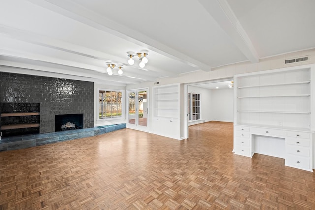 unfurnished living room featuring a tiled fireplace, built in desk, parquet floors, and beam ceiling