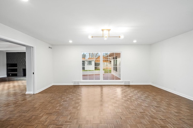 spare room with dark parquet flooring and a chandelier