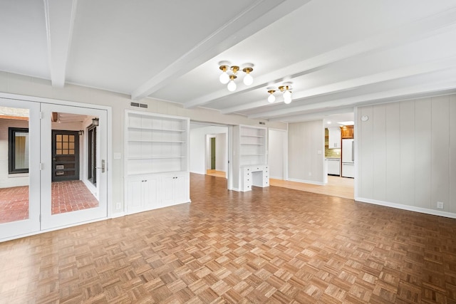 unfurnished living room with built in shelves, light parquet flooring, and beam ceiling