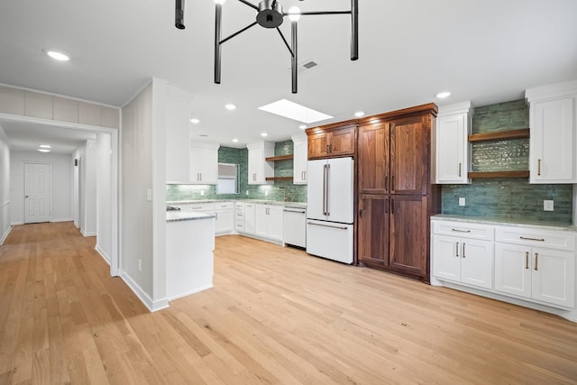 kitchen featuring a skylight, tasteful backsplash, white cabinetry, light hardwood / wood-style floors, and white appliances