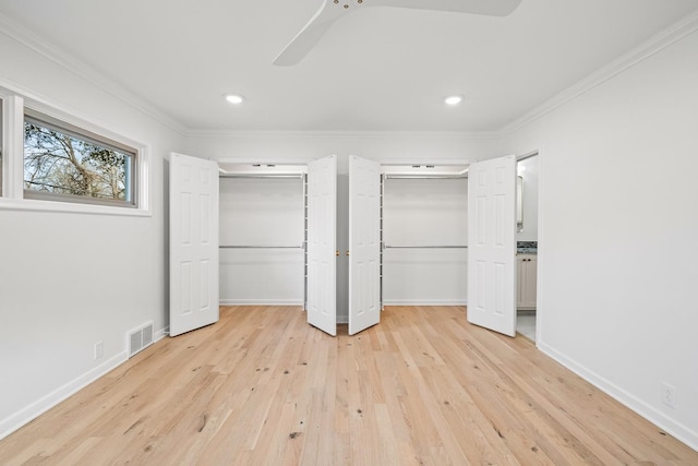 unfurnished bedroom featuring crown molding, ceiling fan, light wood-type flooring, and two closets