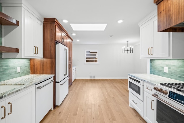 kitchen with high quality fridge, stainless steel microwave, white cabinetry, stove, and white dishwasher