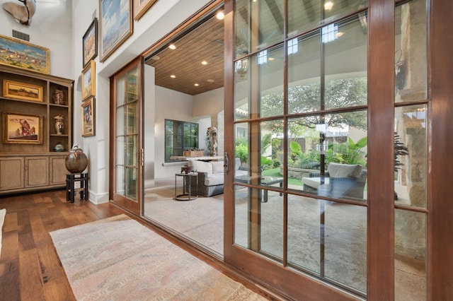 doorway to outside with wood ceiling, a towering ceiling, and wood-type flooring