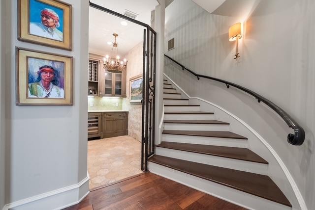 stairs featuring an inviting chandelier, bar area, and hardwood / wood-style floors