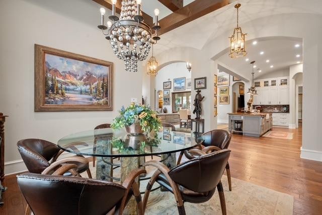 dining room featuring lofted ceiling, a chandelier, and light hardwood / wood-style flooring