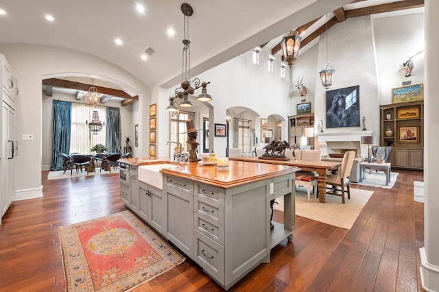 kitchen with sink, decorative light fixtures, lofted ceiling with beams, and a kitchen island