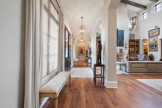 foyer entrance featuring beamed ceiling, wood-type flooring, a high ceiling, and a chandelier