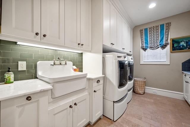 laundry area with independent washer and dryer, cabinets, and sink