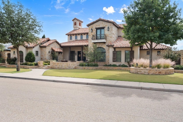 mediterranean / spanish-style home with a front yard and a balcony