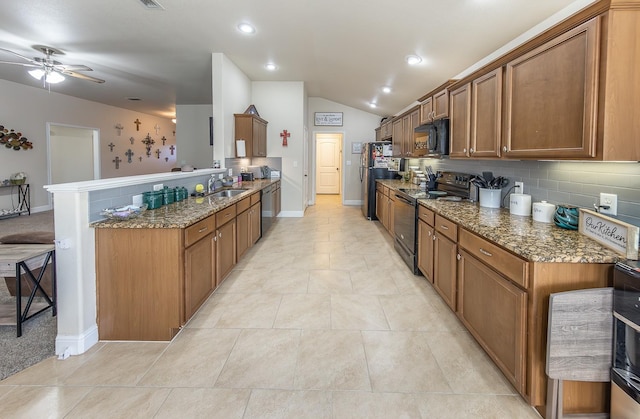 kitchen featuring lofted ceiling, black appliances, kitchen peninsula, dark stone counters, and backsplash