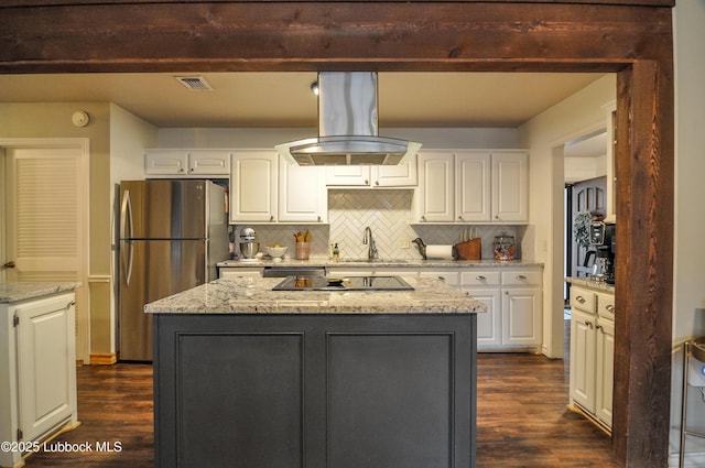 5309 77th St, Lubbock, TX 79424 - kitchen featuring island exhaust hood, freestanding refrigerator, dark wood-type flooring, black electric stovetop, and decorative backsplash