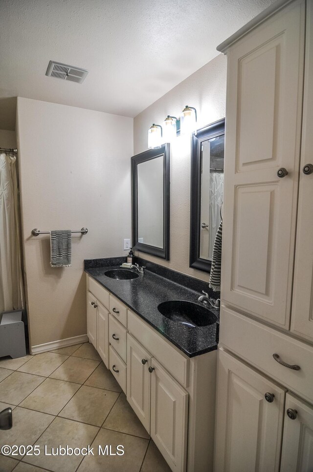 5309 77th St, Lubbock, TX 79424 - full bath featuring double vanity, tile patterned floors, a textured ceiling, and baseboards