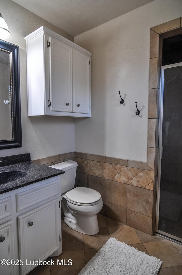 5309 77th St, Lubbock, TX 79424 - full bathroom featuring vanity, toilet, a stall shower, tile patterned flooring, and tile walls