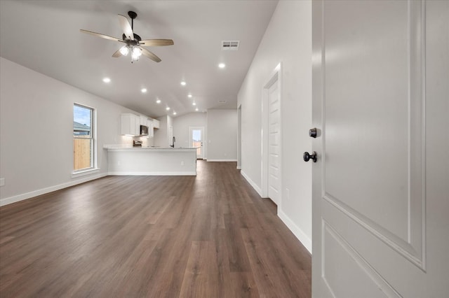 unfurnished living room with vaulted ceiling, plenty of natural light, dark wood-type flooring, and ceiling fan