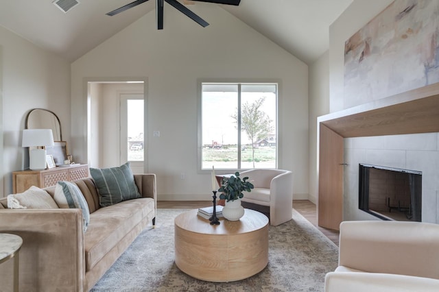 living room with vaulted ceiling, ceiling fan, a fireplace, and light wood-type flooring