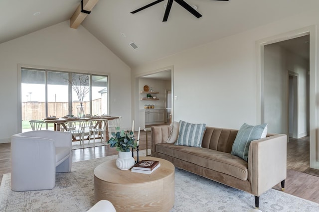 living room with lofted ceiling with beams, ceiling fan, and light wood-type flooring