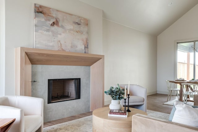 living room featuring lofted ceiling, a fireplace, and light hardwood / wood-style floors