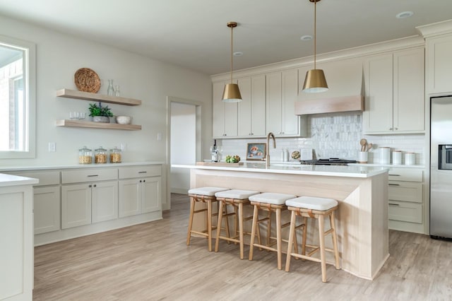 kitchen with pendant lighting, sink, an island with sink, and a kitchen bar