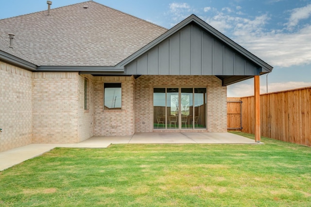 back of house with a patio and a lawn