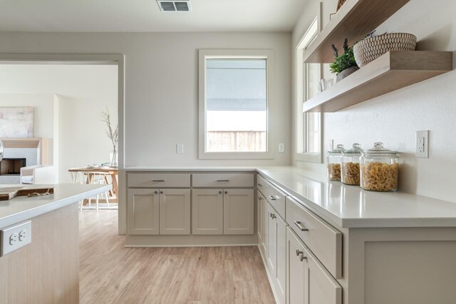 kitchen featuring gray cabinets, kitchen peninsula, and light wood-type flooring