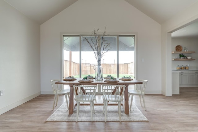 dining space with vaulted ceiling and light wood-type flooring