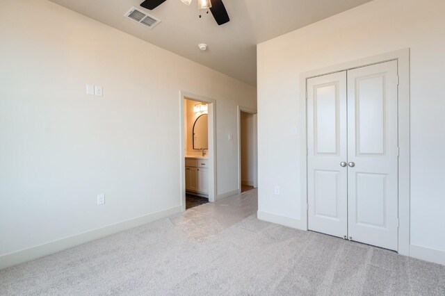 unfurnished bedroom featuring ceiling fan, ensuite bath, and a closet