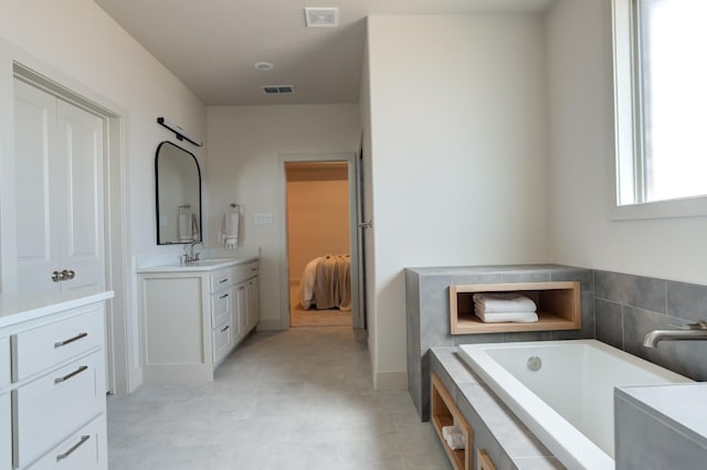 bathroom with vanity and tiled tub