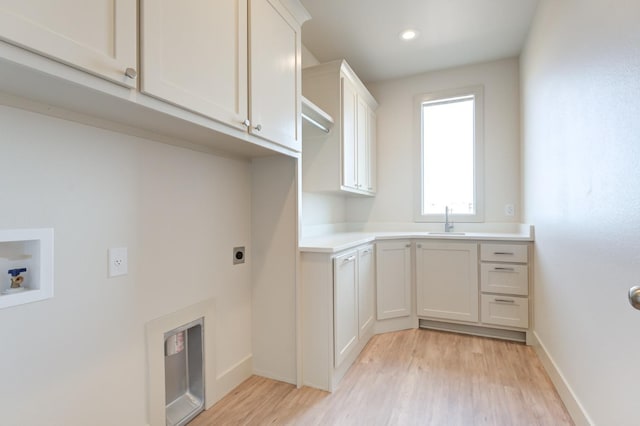 clothes washing area with sink, cabinets, washer hookup, light hardwood / wood-style floors, and hookup for an electric dryer