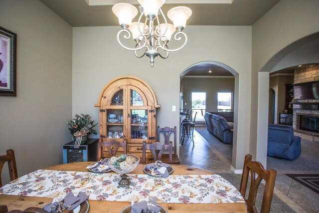 tiled dining area with arched walkways, a notable chandelier, and baseboards