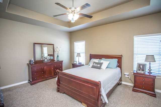 bedroom with a raised ceiling, baseboards, a ceiling fan, and carpet floors